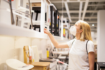 Image showing New normal during covid epidemic. Caucasian woman shopping at retail furniture and home accessories store wearing protective medical face mask to prevent spreading of corona virus