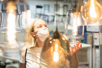 Image showing New normal during covid epidemic. Caucasian woman shopping at retail furniture and home accessories store wearing protective medical face mask to prevent spreading of corona virus