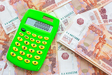 Image showing Against the background of money is a bundle of five-thousandth bills and a calculator with the number one million