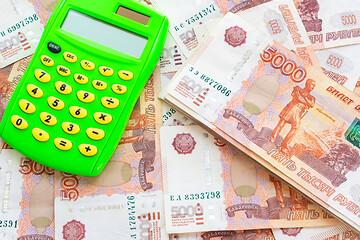 Image showing Against the background of money is a calculator and a pack of five thousandth Russian rubles