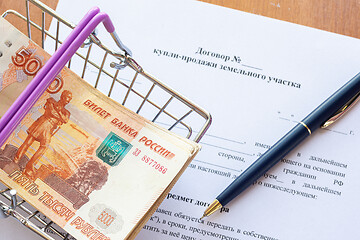 Image showing There is a bundle of money in a grocery basket and a ballpoint pen on the land purchase agreement