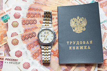 Image showing On a pack of five thousandth bills there is a work book and a watch