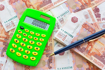 Image showing The number 1,000,000 is written on the calculator, the calculator and the ballpoint pen lie on a pile of money