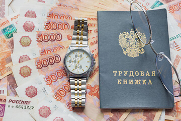 Image showing On a pack of five thousandth bills there is a work book, a watch and glasses
