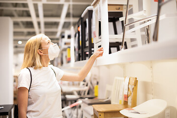 Image showing New normal during covid epidemic. Caucasian woman shopping at retail furniture and home accessories store wearing protective medical face mask to prevent spreading of corona virus