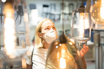 Image showing New normal during covid epidemic. Caucasian woman shopping at retail furniture and home accessories store wearing protective medical face mask to prevent spreading of corona virus