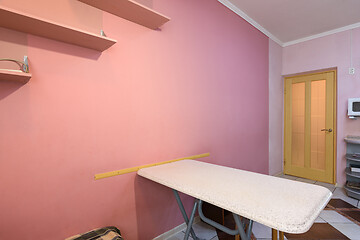 Image showing Fragment of kitchen interior, dining table and part of a painted wall with shelves