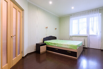 Image showing Bedroom interior with a bed in the middle and a large window opening onto a balcony