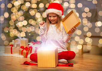 Image showing excited girl in santa hat opening christmas gift