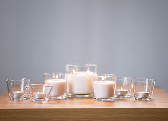 Image showing burning white fragrance candles on wooden table