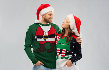 Image showing happy couple in christmas sweaters and santa hats