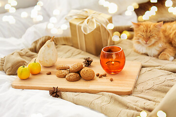 Image showing oatmeal cookies, christmas gift and candle in bed