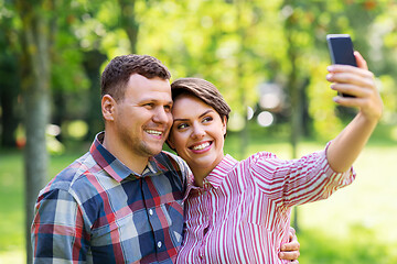 Image showing happy couple in park taking selfie by smartphone