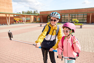 Image showing happy school kids with scooters taking selfie