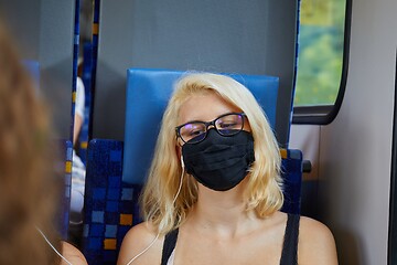 Image showing Young woman on a train wearing mask