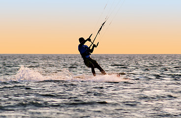 Image showing Silhouette of a kitesurfer on waves of a gulf 