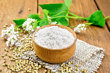 Image showing Flour buckwheat green in bowl with flowers on brown board