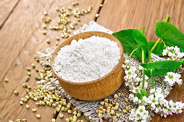 Image showing Flour buckwheat green in bowl with flowers on old brown board