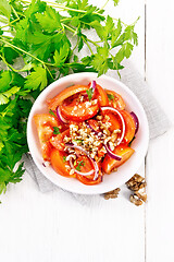 Image showing Salad with tomato and walnut in plate on light board top