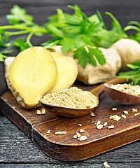 Image showing Ginger ground and flakes in spoons on black wooden board