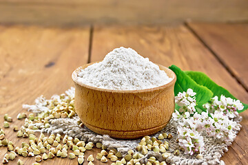 Image showing Flour buckwheat green in bowl with flowers on old wooden board