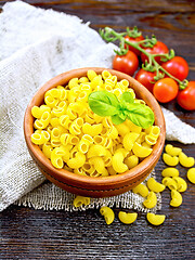 Image showing Elbow macaroni in bowl with tomatoes on board