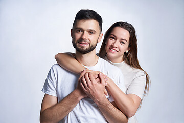 Image showing Smiling young couple hugging, studio portrait over light background