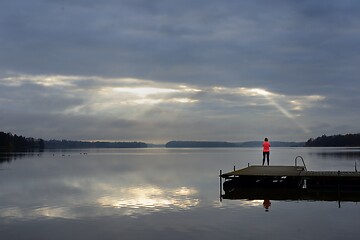 Image showing the sun's rays make their way through the clouds above the lake,