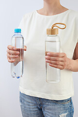 Image showing The woman holds two bottles of glass and plastic of clean fresh water.