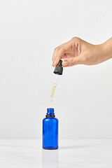 Image showing Woman\'s hand holds pipet of natural extract CBD oil against a light grey background