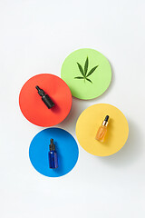 Image showing Colorful round cards with bottles of cannabis CBD oil on a light grey background.