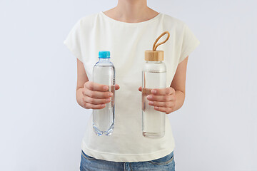 Image showing Glass and plastic bottles of clean fresh water in a woman\'s hands.