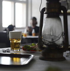 Image showing glass of beer and shrimp salad on a table with a kerosene lamp