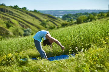 Image showing Young woman doing yoga in green summer meadow