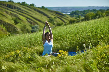 Image showing Young woman doing yoga in green summer meadow