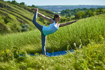 Image showing Young woman doing yoga in green summer meadow