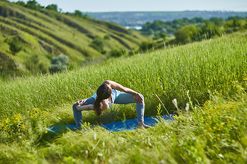 Image showing Young woman doing yoga in green summer meadow