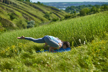 Image showing Young woman doing yoga in green summer meadow