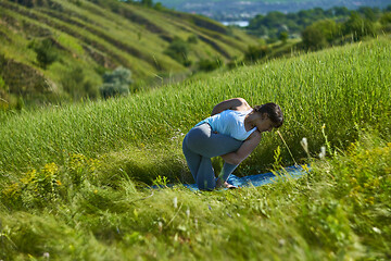 Image showing Young woman doing yoga in green summer meadow