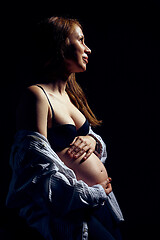 Image showing Profile of pregnant woman over black background feeling calmness with closed eyes