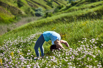 Image showing Young woman doing yoga in green summer meadow