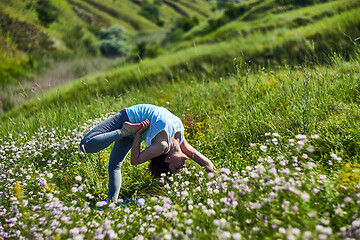 Image showing Young woman doing yoga in green summer meadow