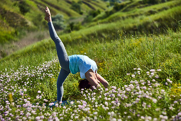 Image showing Young woman doing yoga in green summer meadow