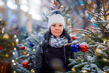 Image showing Woman on the street walks on Christmas day next to Christmas tre