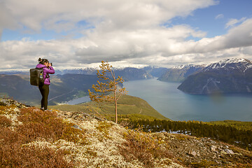 Image showing Nature photographer tourist with camera shoots while standing on