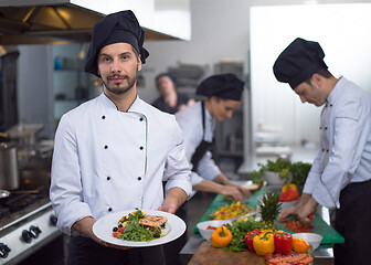 Image showing Chef holding dish of fried Salmon fish fillet