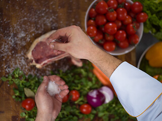 Image showing Chef putting salt on juicy slice of raw steak