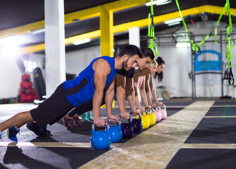 Image showing young athletes doing pushups with kettlebells