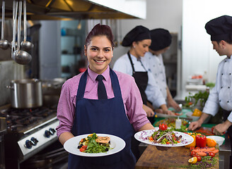 Image showing young waitress showing dishes of tasty meals