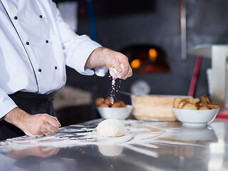 Image showing chef sprinkling flour over fresh pizza dough